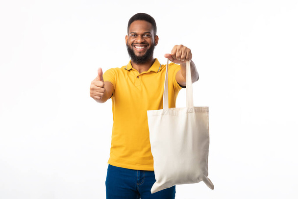 Αφρικανικός άνθρωπος που δείχνει Eco Bag Gesturing Thumbs-Up σε λευκό φόντο - Φωτογραφία, εικόνα
