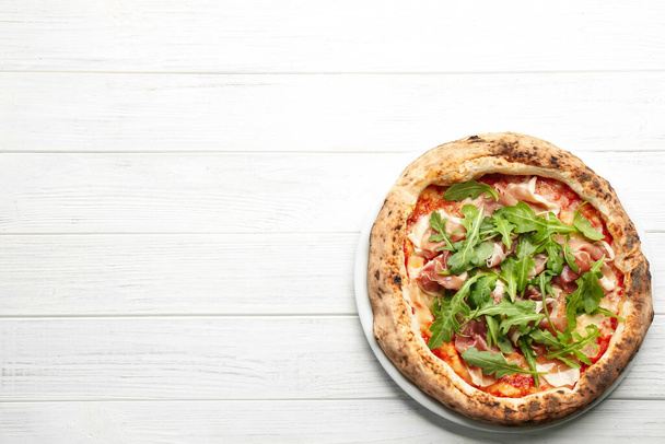 Tasty pizza with meat and arugula on white wooden table, top view. Space for text - Fotografie, Obrázek