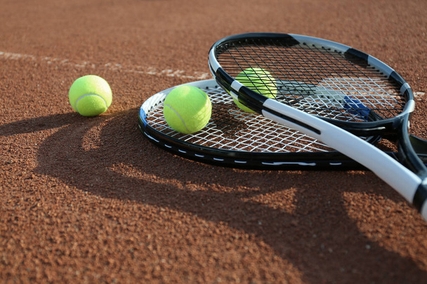Tennis balls and rackets on clay court - Zdjęcie, obraz
