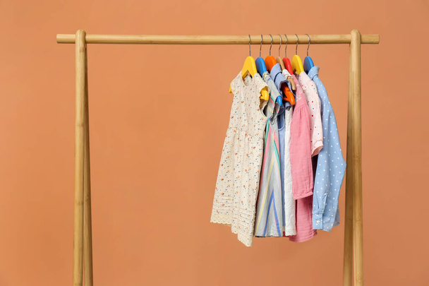 Rack with stylish children clothes on beige background - Fotó, kép