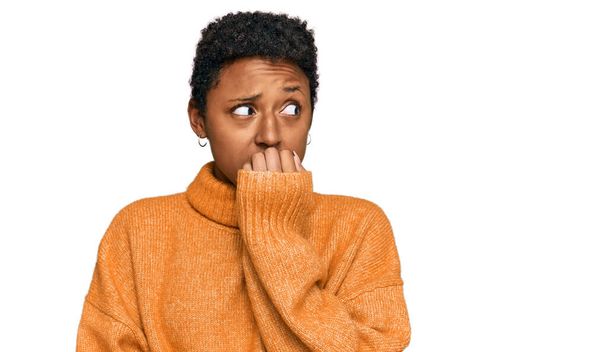 Jeune femme afro-américaine portant des vêtements décontractés à l'air stressé et nerveux avec les mains sur les ongles mordants de la bouche. problème d'anxiété.  - Photo, image