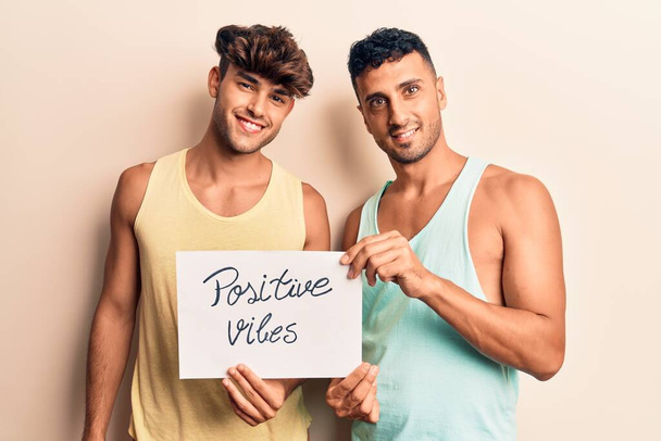 jong gay paar holding positief vibes banner kijken positief en gelukkig staan en glimlachen met een zelfverzekerde glimlach tonen tanden  - Foto, afbeelding