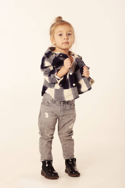 cute little blond baby girl in black boots, jeans, checkered shirt with copy space isolated on white - Foto, immagini