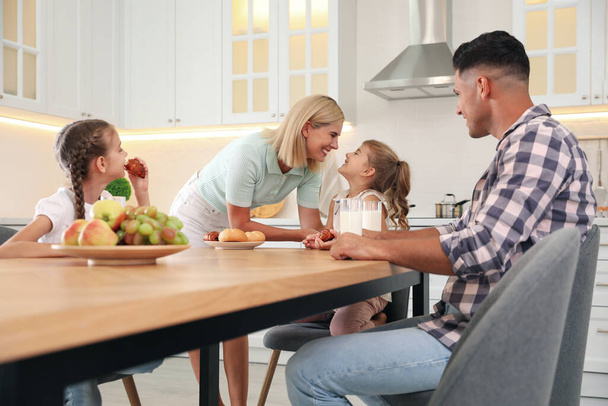 Happy family eating together at table in modern kitchen - Valokuva, kuva