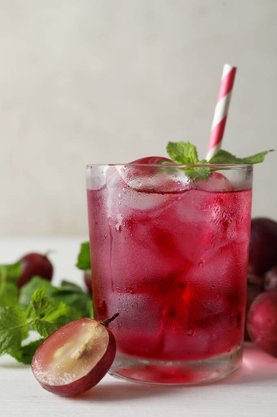 Delicious grape soda water with mint on white table. Refreshing drink - Фото, изображение