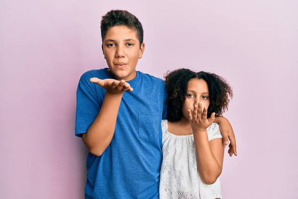 Young hispanic family of brother and sister wearing casual clothes together looking at the camera blowing a kiss with hand on air being lovely and sexy. love expression.  - Photo, image