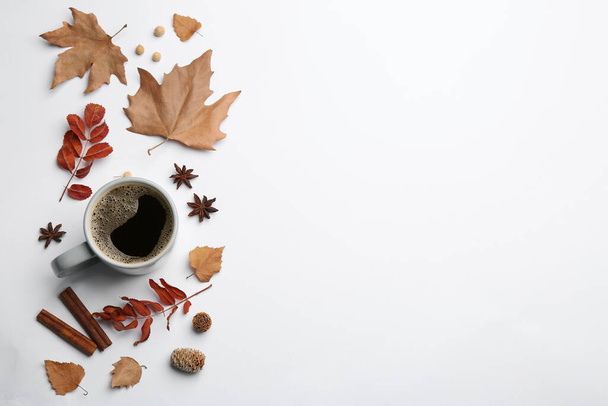 Flat lay composition with cup of hot drink and autumn leaves on white background, space for text. Cozy atmosphere - Фото, изображение