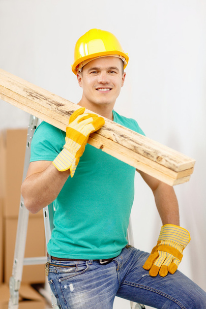 Smiling manual worker in helmet with wooden boards - Foto, Imagen