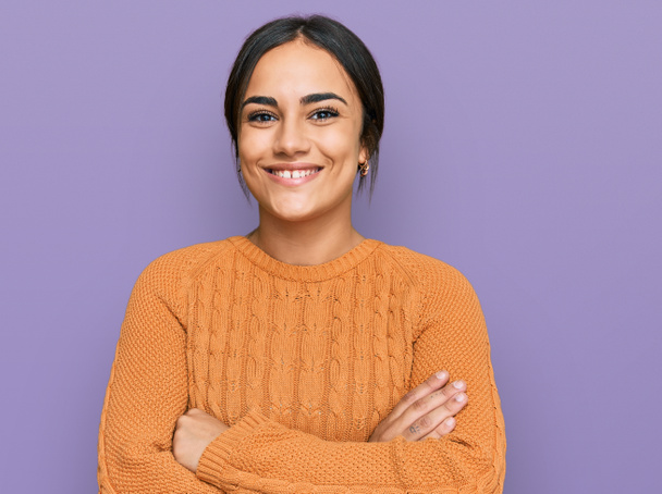 Jeune femme brune portant un pull d'hiver décontracté visage heureux souriant avec les bras croisés regardant la caméra. personne positive.  - Photo, image