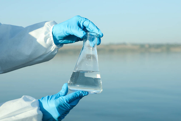Scientist with conical flask taking sample from river for analysis, closeup - Valokuva, kuva