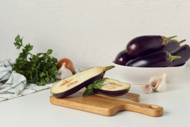 Cut eggplant and basil on white table - Foto, Imagen