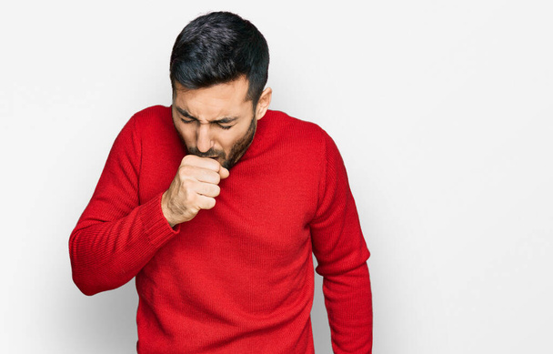 Hombre hispano joven que usa ropa casual sintiéndose mal y tosiendo como síntoma de resfriado o bronquitis. concepto de atención sanitaria.  - Foto, imagen
