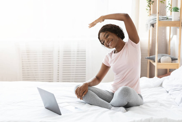 Ευτυχισμένη μαύρη γυναίκα κάνει πρωινή άσκηση στο σπίτι - Φωτογραφία, εικόνα