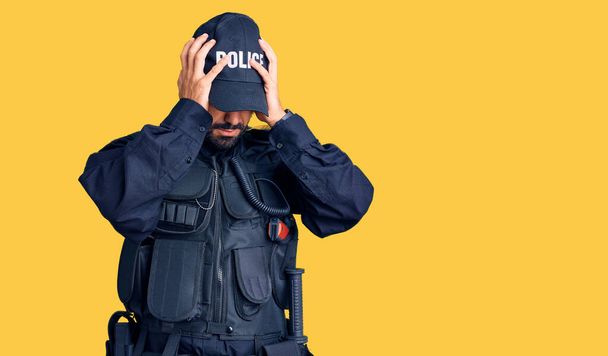 Polis üniforması giyen genç İspanyol adam acı ve migren yüzünden çaresiz ve stresli bir şekilde baş ağrısı çekiyor. Eller başının üstünde..  - Fotoğraf, Görsel