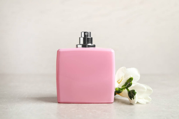 Bottle of perfume and beautiful freesia flower on light table - Fotografie, Obrázek