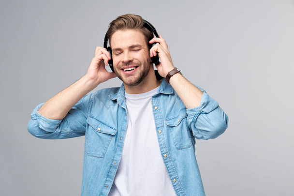 Close up portrait of cheerful young man enjoying listening to music wearing casual jeans outfit - Zdjęcie, obraz