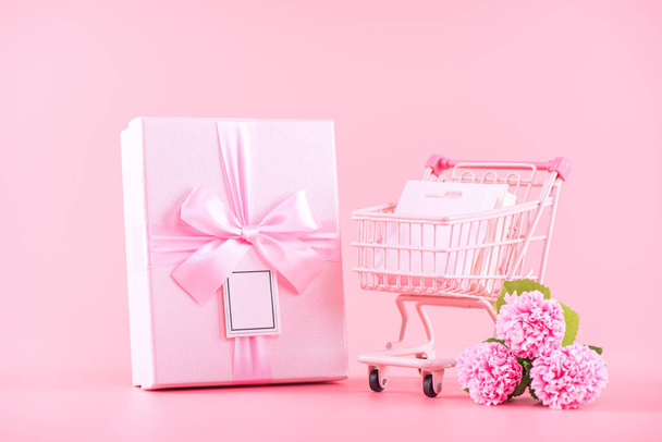 Mother's Day holiday gift design concept, pink carnation flower bouquet with wrapped gift box isolated on pink background, copy space. - Photo, Image