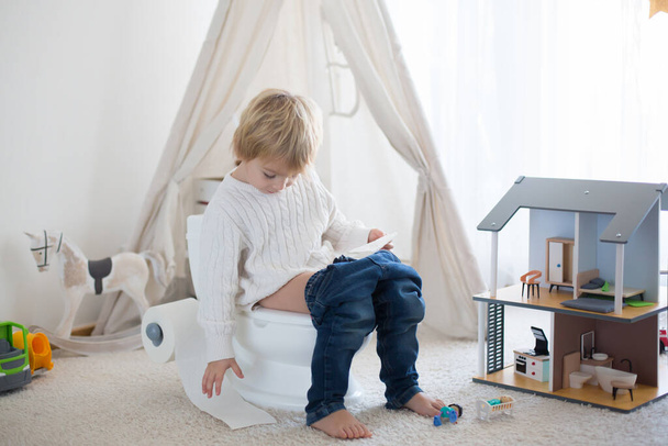 Criança bonito, menino, sentado em um banheiro bebê potty, brincando com brinquedos - Foto, Imagem