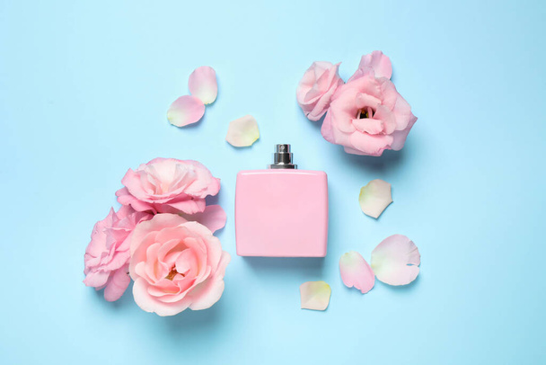 Flat lay composition with bottle of perfume and flowers on light blue background - Foto, Imagen