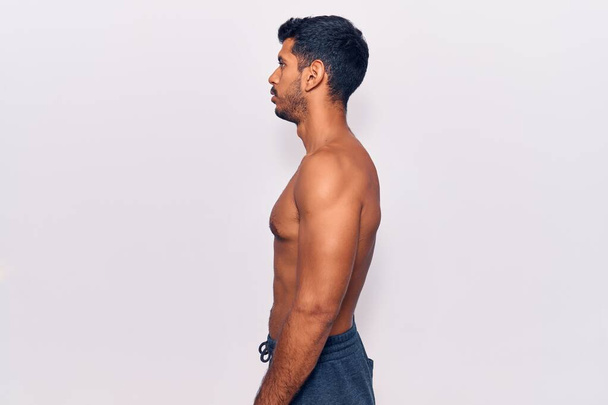 Young latin man standing shirtless looking to side, relax profile pose with natural face with confident smile.  - Foto, afbeelding