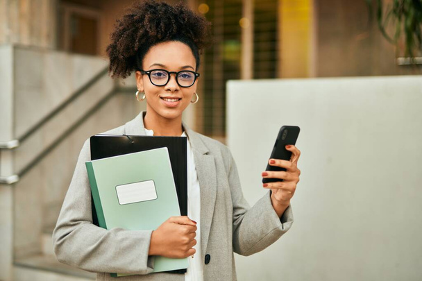 Young african american businesswoman smiling happy using smartphone at the city. - 写真・画像