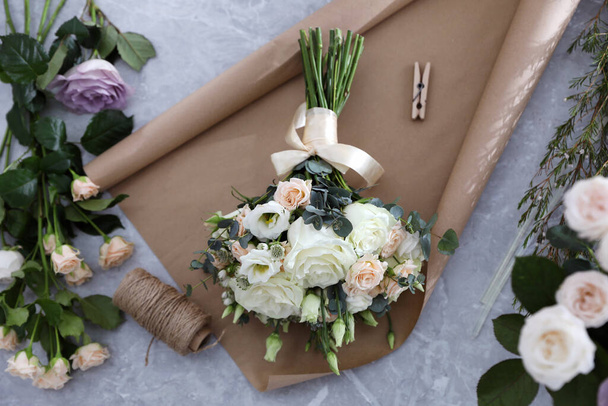 Krásná svatební kytice a papírový list na světle šedém mramorovém stole, pohled shora - Fotografie, Obrázek