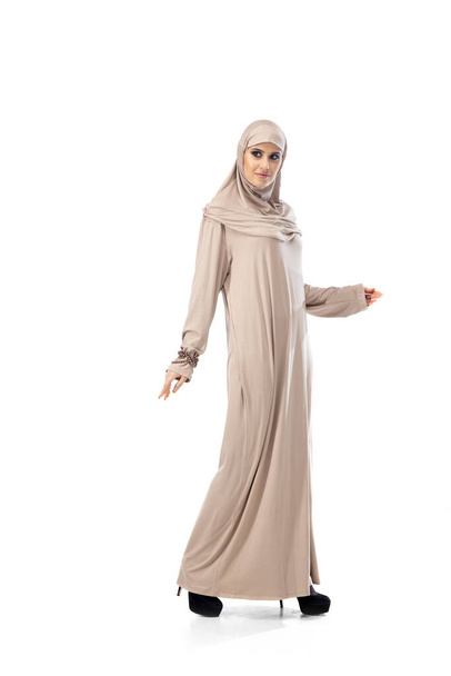 スタジオバックで孤立したスタイリッシュなヒジャブ姿でポーズをとる美しいアラブ女性。ファッションコンセプト - 写真・画像