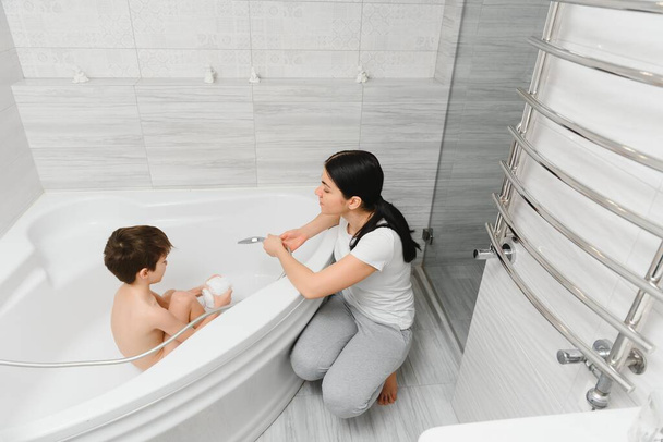 Mother washing little son in bathroom - Valokuva, kuva