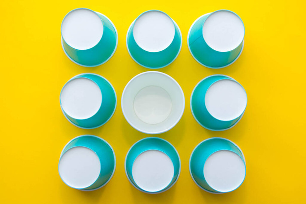 Pattern from blue paper disposable cups on yellow background. Set for party. Top view. Minimalist Style. Copy, empty space for text. - Photo, Image