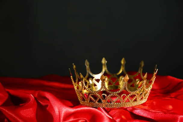 Beautiful golden crown on red fabric. Fantasy item - Photo, Image