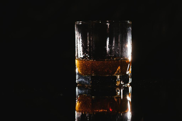 Whiskey glass black background shiny - Fotó, kép