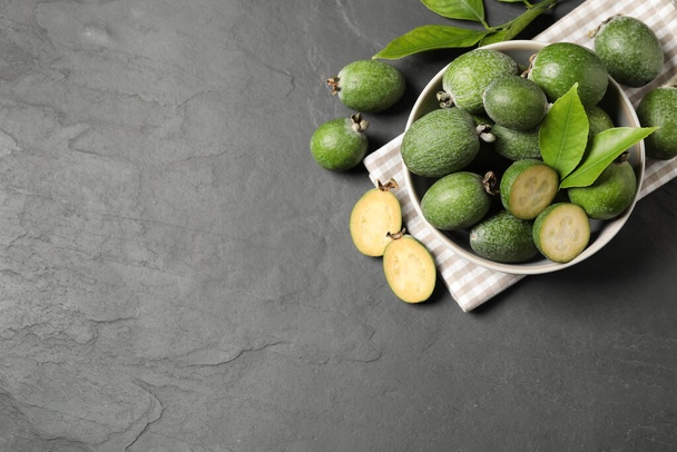 Flat lay composition with fresh green feijoa fruits on black table, space for text - 写真・画像