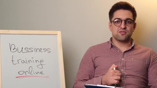 Fiatal fiú szemüveges van birtoklás online üzleti tréning órák beszél a kamera előtt, és mosoly mellett egy fórumon - Felvétel, videó