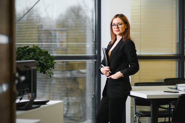 Portrait of a cute young business woman smiling, in an office environment - Foto, imagen