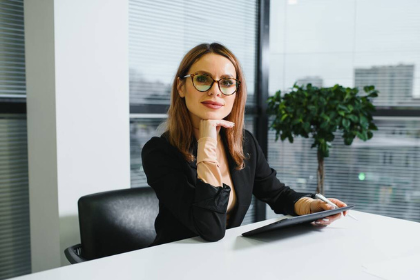 Portrait of successful female sitting in office - Zdjęcie, obraz