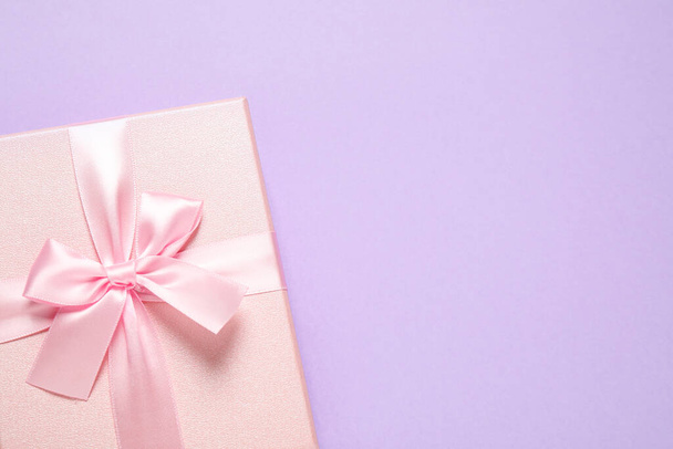 Pink gift box on violet background, top view. Space for text - Фото, изображение