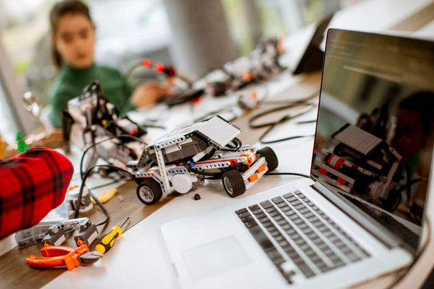 Grupa szczęśliwych dzieci programuje zabawki elektryczne i roboty w klasie robotyki - Zdjęcie, obraz