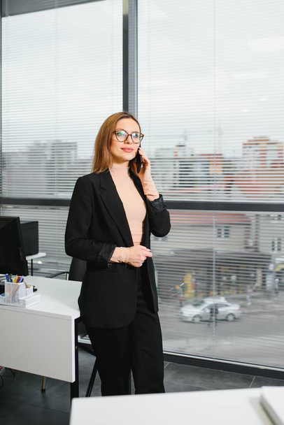 Confident business woman stands in the office - Foto, afbeelding