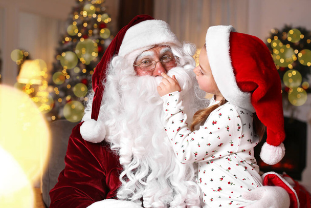Santa Claus and cute little girl in room decorated for Christmas - 写真・画像