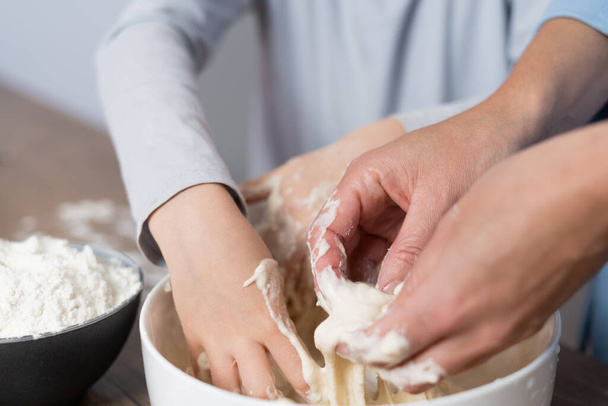 Matka i córka z mąką razem w kuchni przygotowują ciasto w misce. Ręce do góry.. - Zdjęcie, obraz