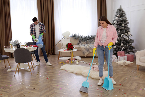 Couple cleaning messy room after New Year party - Foto, imagen