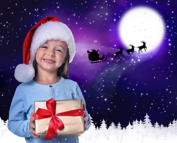 Cute little child and Santa Claus flying in his sleigh against moon sky on background. Christmas celebration - Foto, immagini