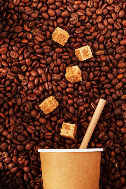 Grains of coffee drink and pieces of cane sugar in zero waste paper cup on grains background. Plastic free concept. Selective focus. - Foto, Imagen