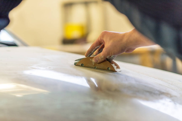 Grinder in the hands of a man who sharpen a car varnish in the car shop. - 写真・画像