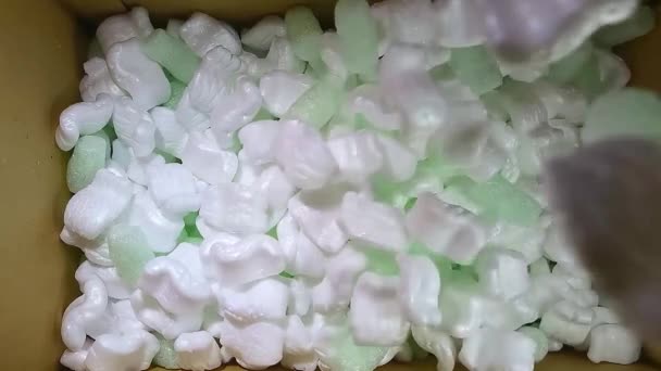 zöld hab gumi és fehér styrofoam töltőanyag esik egy kartondobozba - Felvétel, videó