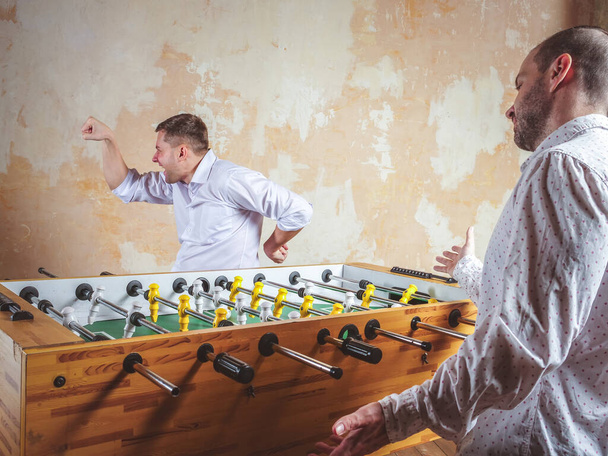 A man celebrates a victory in table football. Evening activities and relaxation. - Foto, afbeelding