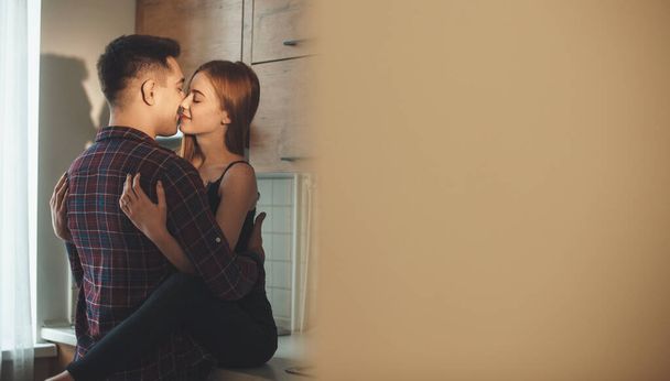 Takaisin Katso kuva valkoihoinen nainen pisamia syleilee hänen rakastaja molemmat jalat keittiössä suudella - Valokuva, kuva
