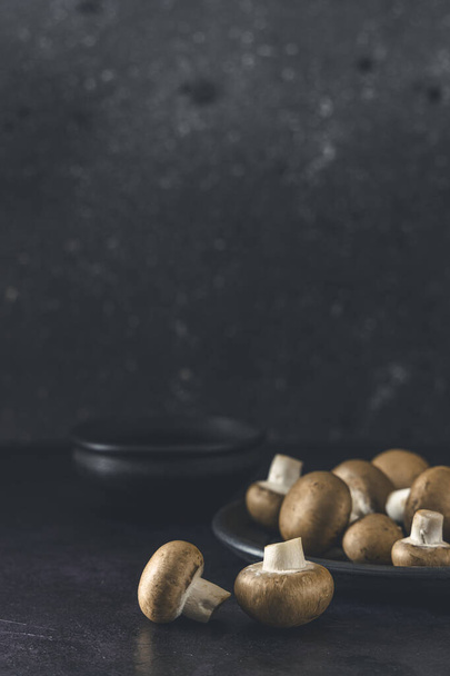 Raw mushrooms champignons on black background, cooking fresh champignons - Photo, Image