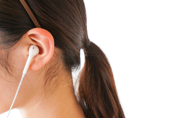 Mujer joven escuchando música en auriculares sobre fondo blanco - Foto, Imagen