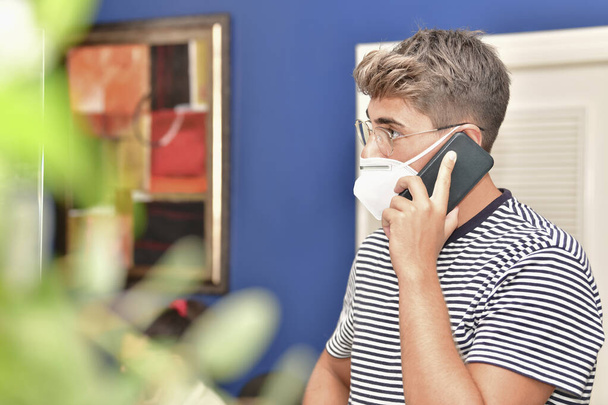 Gros plan d'un jeune homme utilisant un masque facial et parlant sur son téléphone - Photo, image